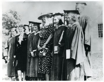 Mrs. Eleanor Roosevelt is standing with the graduating class and teacher at Arthurdale. 