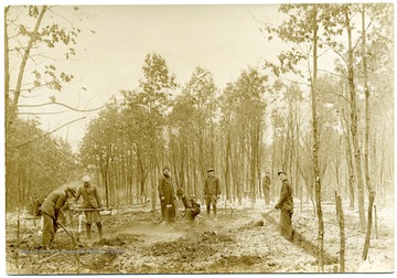 Men in snowy woods dig a foundation for the first house in Arthurdale.