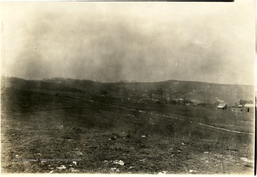 View of a field and farm buildings in the distance on the right.