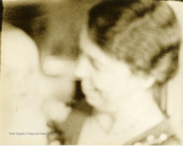 Blurry image of Eleanor Roosevelt holding a baby. 'Mrs. Eleanor Roosevelt makes talkies for farewell speech.'