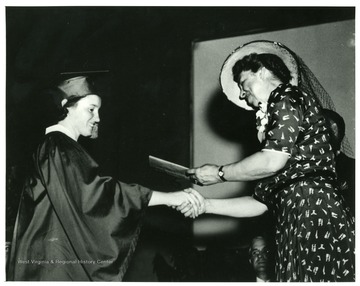 Eleanor Roosevelt is presenting a diploma to a graduate of Arthurdale High School. 'A print from the Franklin D. Roosevelt Library Collection. This print is furnished for your files and must not be reproduced without the owner's permission.'