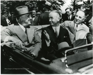 FDR speaks with Senator Matthew M. Neely and Governor Homer A. Holt while riding in a car at Reedsville, W.Va. during visit to the Arthurdale. 'A Print from the Franklin D. Roosevelt Library Collection.  This print is furnished for your file and must not be reproduced without the owner's permission.'