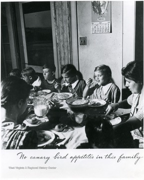 Family sitting down to a meal. Title at the bottom reads: "No Canary Bird Appetites in this Family". 'Album 359, FSA - Arthurdale W. Va. A print from the FDR Library collection. This print is furnished for this file and must not be reproduced without the owner's permission.'