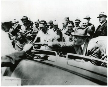 Large crowd gathers around the car of Franklin D. Roosevelt as he leans to pet A cow of local farmer. 'A print from the Franklin D. Roosevelt Library Collection.  This print is furnished for your file and must not be reproduced without the owner's permission.  Owner:  UPI (Acme)' On 6/8/05 spoke with Mark Renovitch, archivist, Roosevelt Library who stated that reproduction of this image is alllowed for personal or research use. If the image is to be published , permission must be attained from the Bettman Archive, owned by Corbis, which now posseses the U.P.I. photo archive.