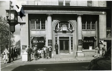 Townspeople are standing in front of the Raleigh County Bank in Beckley, West Virginia.