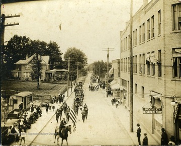 Townspeople are watching members of a parade marching down a street in Beckley, West Virginia.  