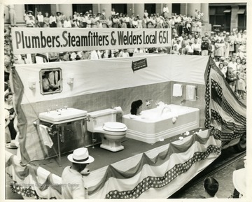 Complete bathroom with a woman in a bathtub serves as a float for the Plumbers, Steamfitters, and Welders union.