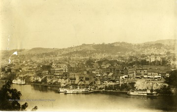 A picture postcard of Charleston, West Virginia.  Boats along shore of river.
