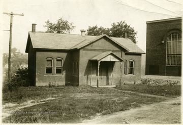 Small brick schoolhouse with gabled entrance.  Stansbury Hall is visible in the right side of the photograph.  In the 1940s and 50s, West Virginia University used this school as a grade school for training eductaion majors.  It was called the WVU Laboratory Elementary School. The building was an African-American school prior to WVU's use of the building.