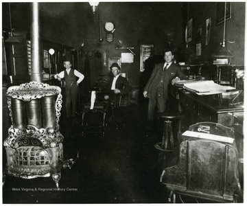 Interior view of the Clarksburg Light and Heat office in Clarksburg, W. Va.  Large heating stove in the right foreground. 