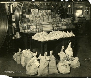 Interior view of National Bank of Fairmont.  Money bags and stacks of cash money in front of the vault 'after the rush, June 1930.'