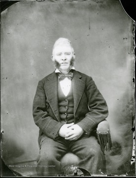 Portrait of a seated man with large sideburns.