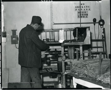 Employee working with a broom in a lathe at the Reliable Broom Plant in Grafton, West Virginia.