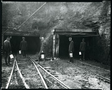 Five coal miners carrying lunch buckets enter shafts at an unidentified coal mine near Grafton, West Virginia.