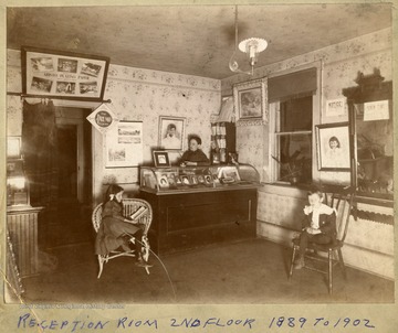 Reception room on the 2nd floor in Grafton, W. Va.  Woman standing behind a counter, two children sitting in chairs.