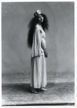 A woman with long curly hair is standing.