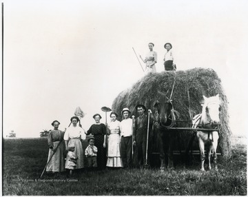 Group of people, some from the Aegerter family, standing with horses pulling a large bale. Helvetia, W. Va.