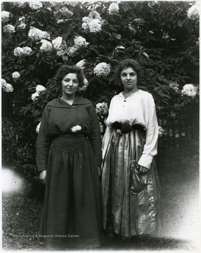Two women standing in front of blossoming bush in Helvetia, W. Va.