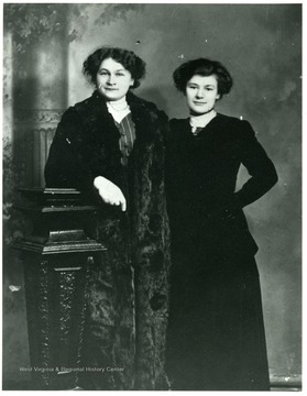 Two women (L- Babette Kolar Schneider R- a friend) standing together for a studio portrait.