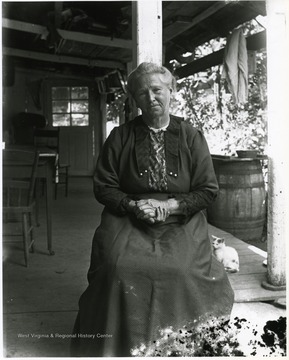 Older woman sitting alone on a porch.  Cat in the background.  Helvetia, W. Va.