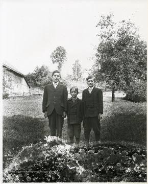 Three young boys wearing suits are standing in a field in Helvetia, West Virginia.
