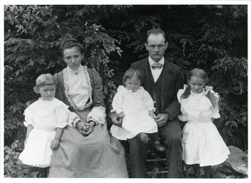 Katharine Rohner Stadler and Walter Stadler are posing with their children Bertha, Louise, and Lydia near some trees.