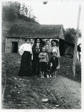 A family and their dog are standing in front of a house in Helvetia, West Virginia.