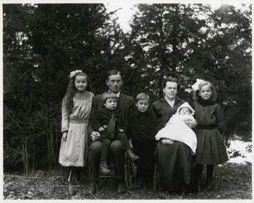 An unidentified family of seven seated outside for a portrait, Helvetia, West Virginia.