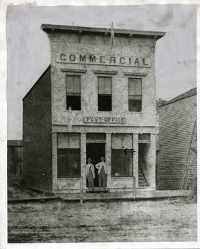 Two men are standing in the doorway of the Commerical Building Post Office in Huntington, West Virginia.