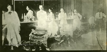 Barbers are standing next to their chairs.