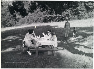 Peopled seated at a picnic table in an unidentified Huntington, Park.  