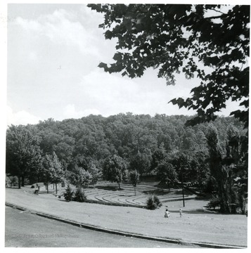 People seated in a field near the sloping, circular terraces.