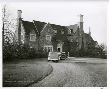 Two automobiles are parked in the driveway of E.P. May's stone house in Huntington, West Virginia.