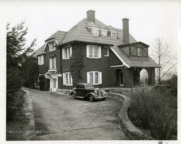 An automobile is parked in front of a brick residence that is possibly the home of O. T. Frick in Huntington, West Virginia.