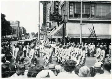 Soldiers marching in a military parade while people stand on the streets and watch, Huntington, W. Va.