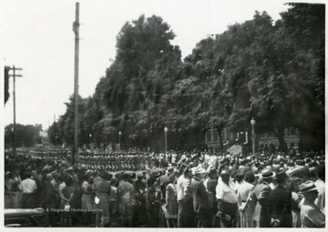 Large group of soldiers marching in a parade while a crowd stands on the street and watches the parade, Huntington, W. Va.