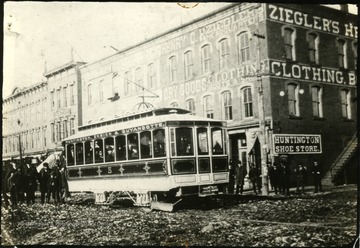 People riding on a Huntington, Ensign, and Guyandotte street car, the first electric street car in Huntington.  Car is in front of the Huntington Shoe Store and other buildings, Huntington, W. Va.