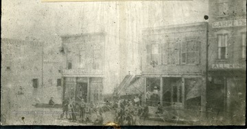 '1884 Flood.  3rd Ave. at 10th St. showing Cammack's, Gideon's, and Holswade's stores, also fire department on raft.