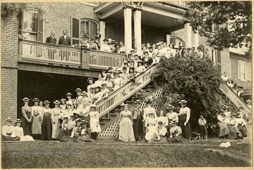 Ladies in dresses pose for a picture on the steps of a brick building.