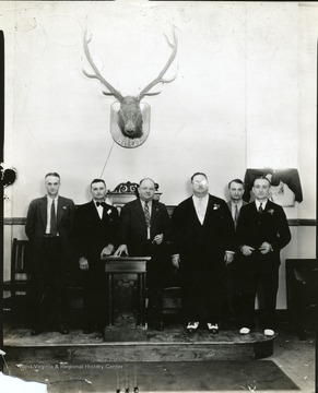 Members stand in a row with a moose on the wall.
