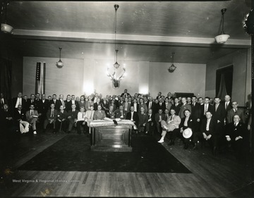 Large group of Elk Lodge members.  An elks head is on the back wall as well as in the center of the group.