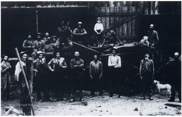 'This picture was taken in 1907 in the back of Samuel Mullett's barn.  Jacob Hassig and Will Berger owned the thrashing machine.  Many of these neighbors were relatives.  Family and neighbors could always be relied on to help on Doolin.  Row 1: Andy Goddard, Frank During, Ed Schupbach, Lewis Durig, John Kocher, Albert Durig, Harry Mullett, Samuel Mullett, and Adolph Durig.  Row 2: Charles Goddard, Will Berger, Sam Kocher, Jacob Hassig, Charles Fisher, John Grossenbach, Wilbert Kocher, Jesse Mullett, Charles Durig.'