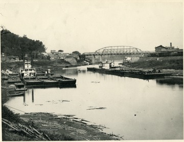 Barges are on the river.  Bridge is visible.