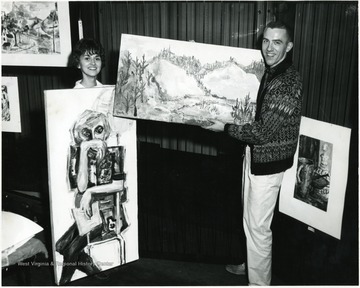 Two students display their paintings.