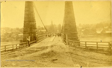 People can be seen walking on bridge, and one person standing at beginning of bridge to the left. Photo Given to Dr. Core by A. C. Shirley