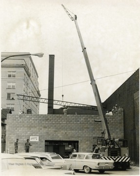 A crane works on placing a steel beam for a building in Morgantown.