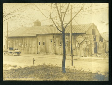 A horse-drawn carriage is parked in front of the Wallace House Stables, 'facing the Junior High site on Spruce Street; Wiles Block, Stable End.' 