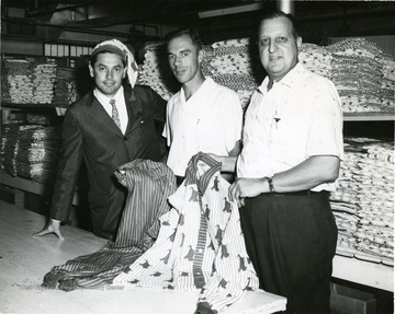 Three men showing off products of pajama factory. 