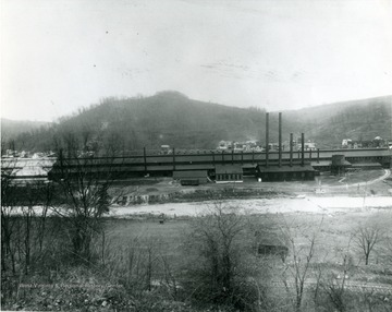 American Sheet and Tin Plate Company located in Sabraton, W. Va., near Morgantown, W. Va. Houses on the far side of the factory. Bare ground on near side of factory. 