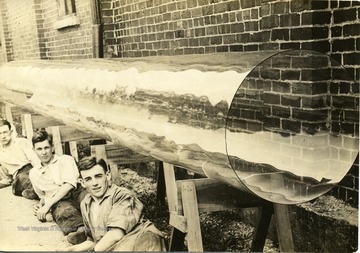 Young men sitting beside glass tubing created at glass factory at Marilla in Morgantown, W. Va. 
